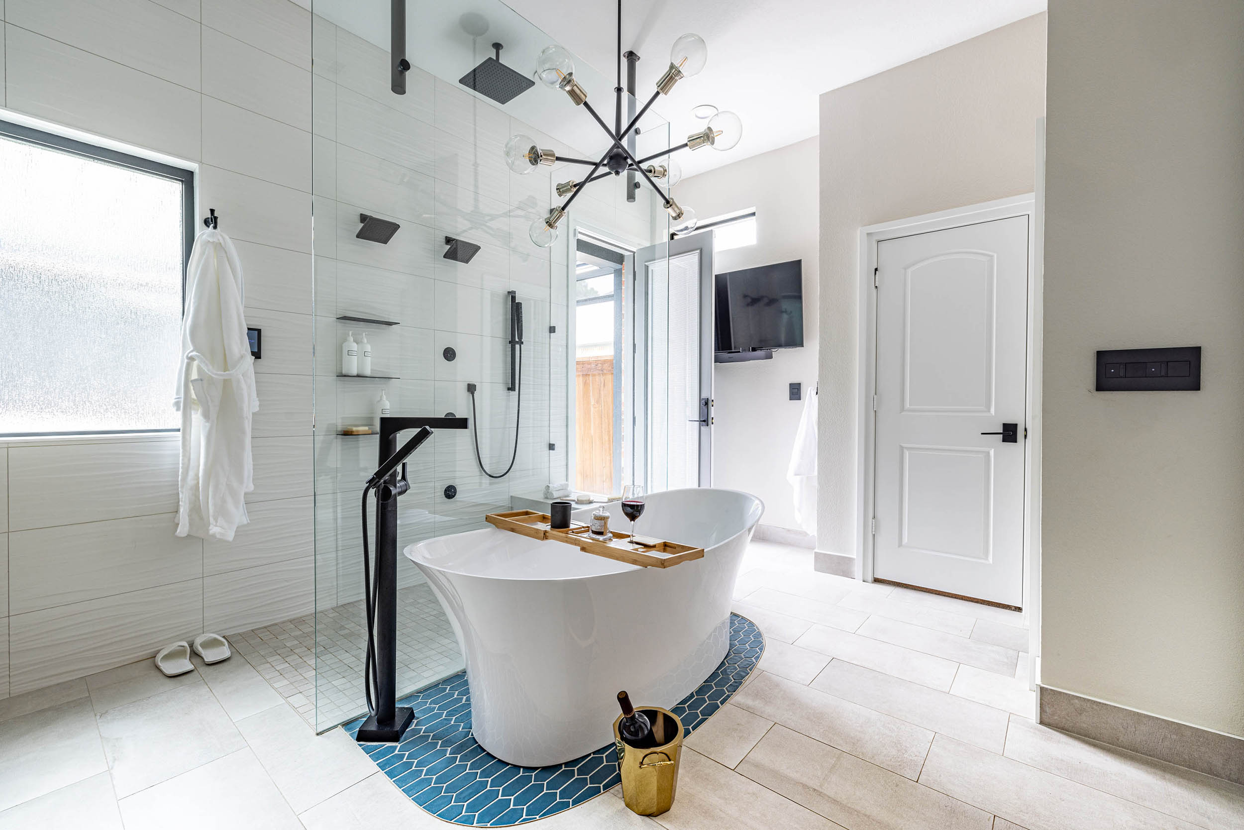 Birkenfeld_Bathroom renovation with light fixture standing tub with shower with multiple showerheads mounted TV in corner indoor-outdoor door to patio in Keller Texas