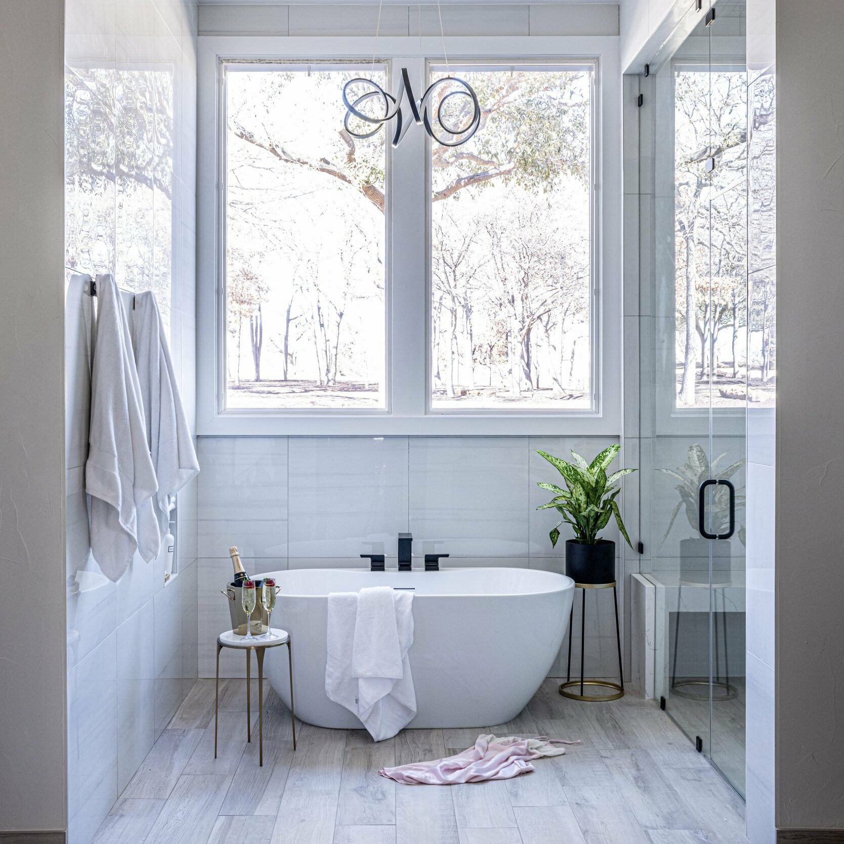 Basler_Bathroom renovation with stand-alone bathtub underneath eyecandy light fixture under bright window alongisde steam shower in Trophy Club Texas